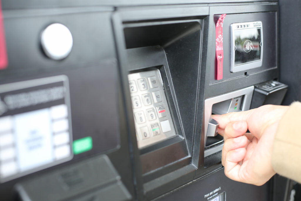 hand swiping credit card at fuel pump station.